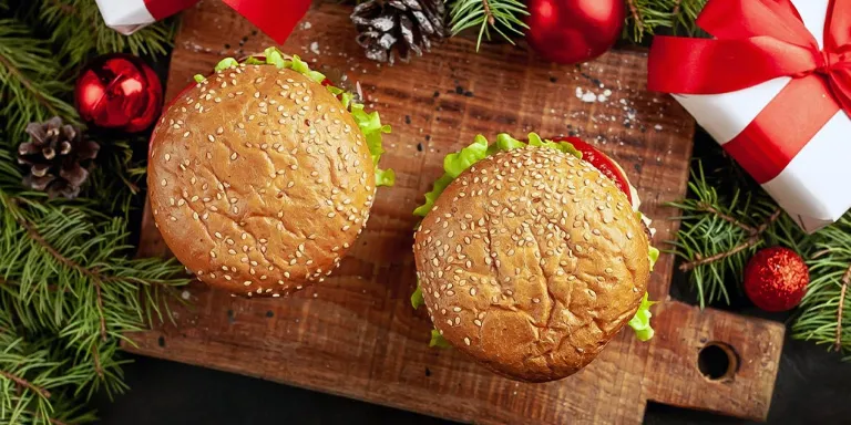 Burger auf einem Holzbrett mit Weihnachtsdeko und kleinen Geschenken